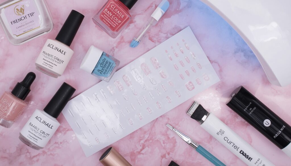 french tip nail designs 2026 at home – flat lay of nail supplies including guide stickers LED lamp polish detail brush and topcoat on pink marble